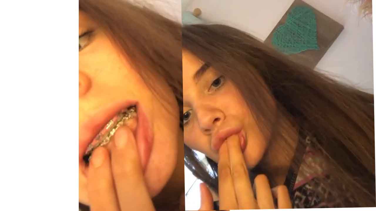 Girl with braces practicing with her fingers how to suck a Dick